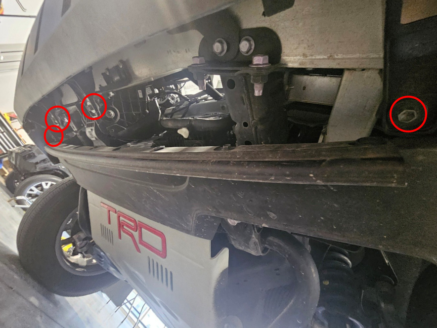 Four lower front-end bolts marked beneath the bumper